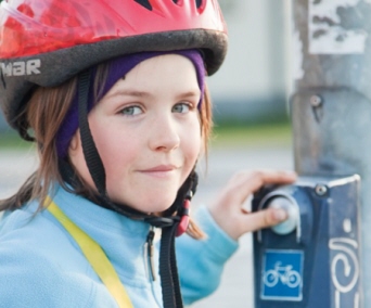 En flicka i cykelhjälm väntar vid övergångsställe. Foto: Scandinav