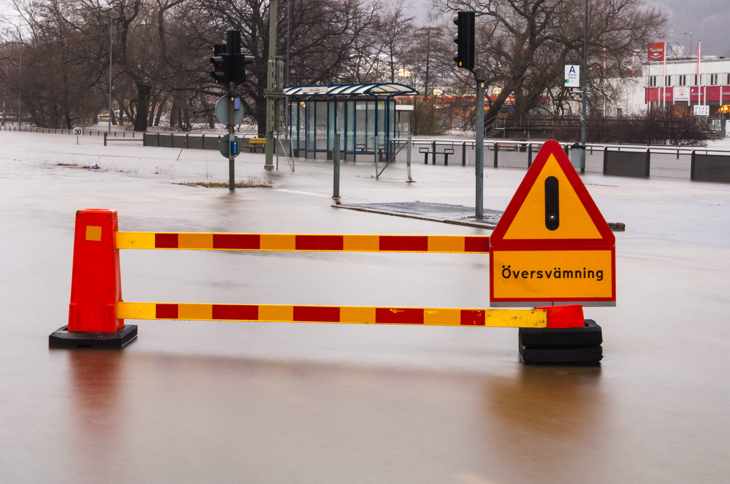 Översvämmad gata med varningsskyltar.