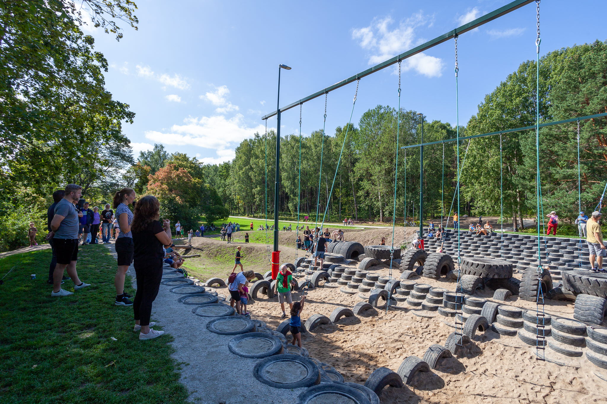 Barn och vuxna som leker i lekpark tillsammans.