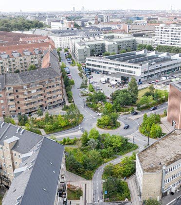 Flygfoto som visar bostadshus, gator och en grön rondell.