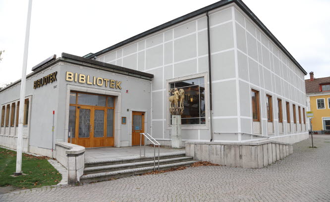 Bibliotek i en grå byggnad med guldbokstäver över entredörren.