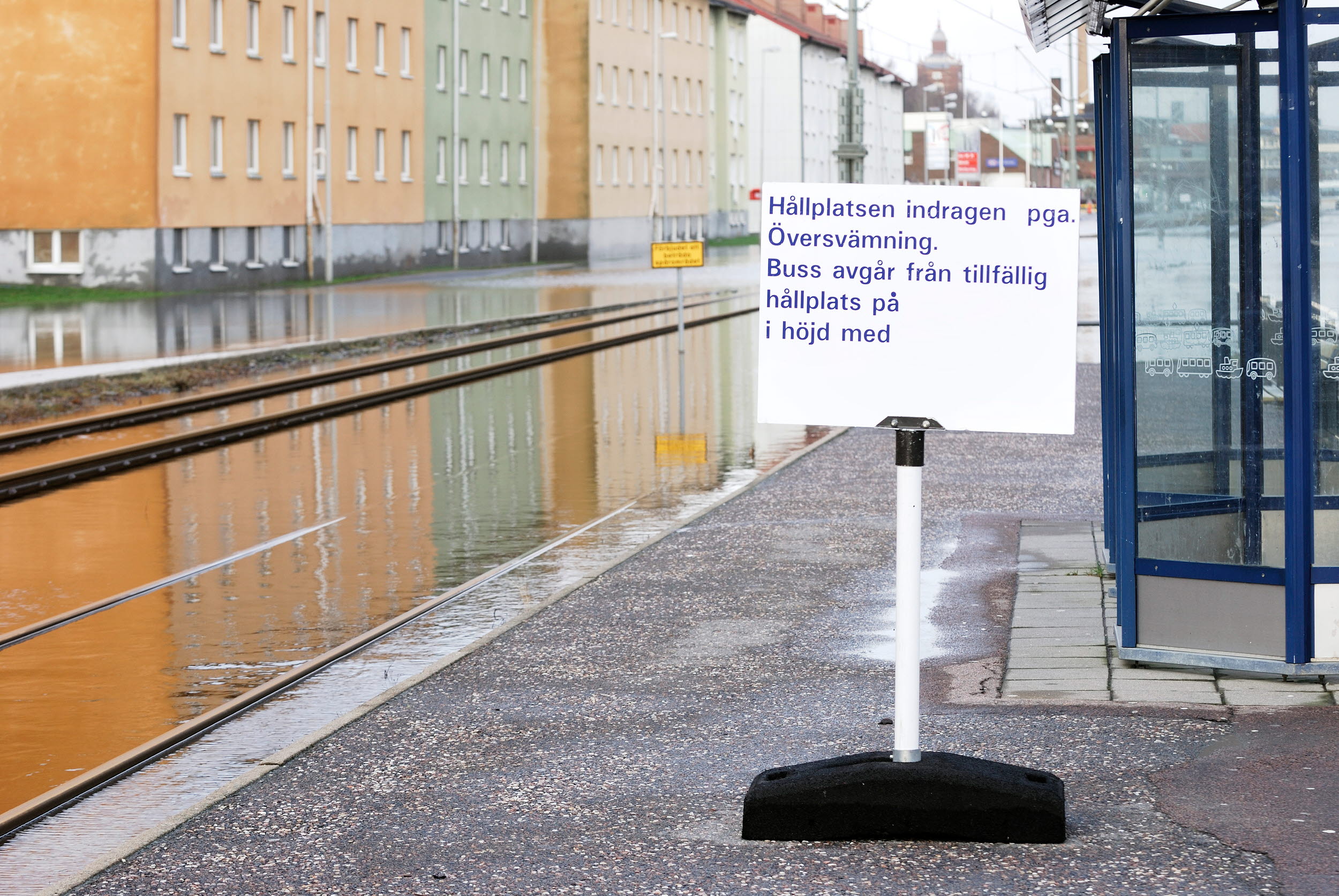 Foto på indragen busshållplats på översvämmad gata.