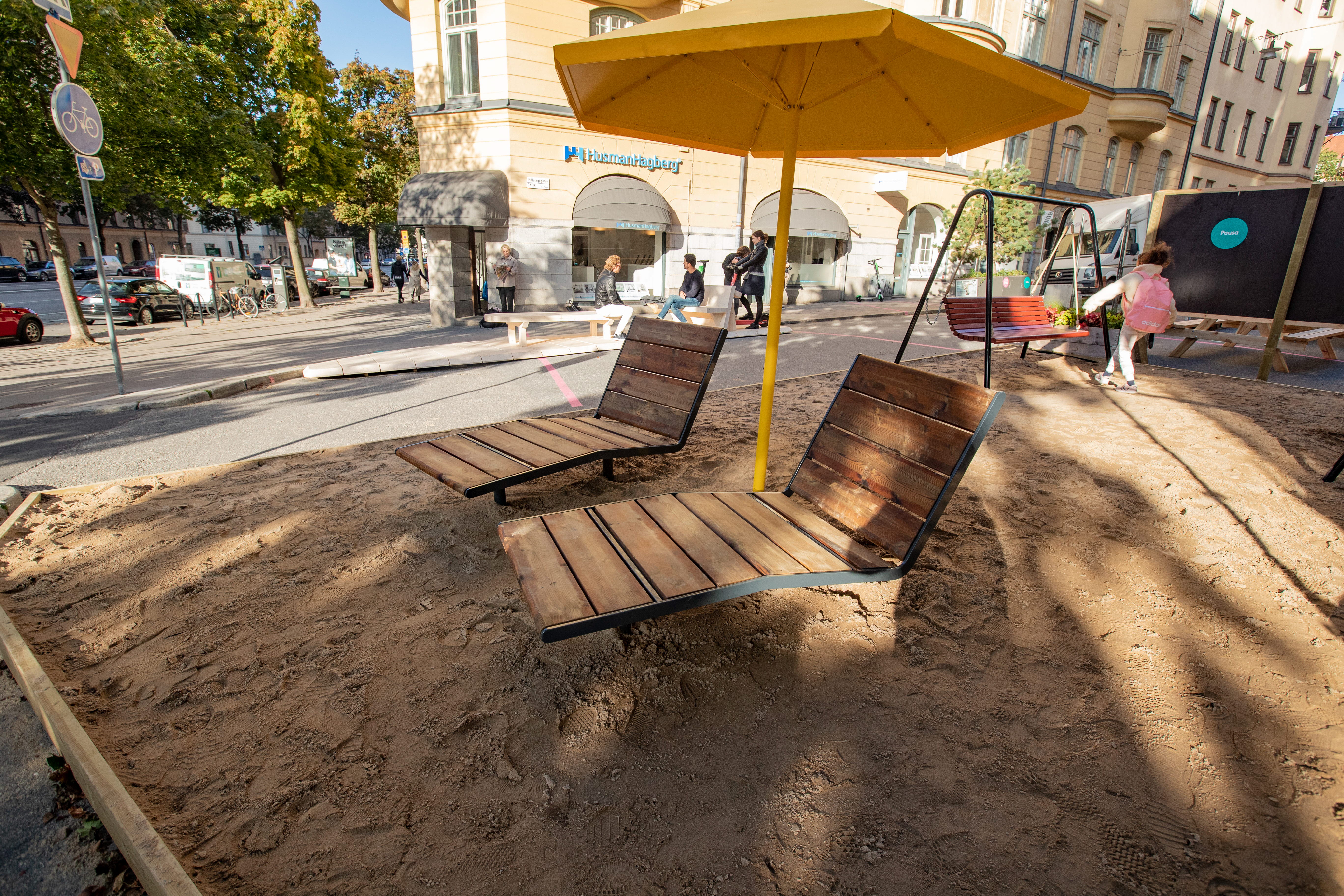 Foto på sand med solstolar och ett gult parasoll.