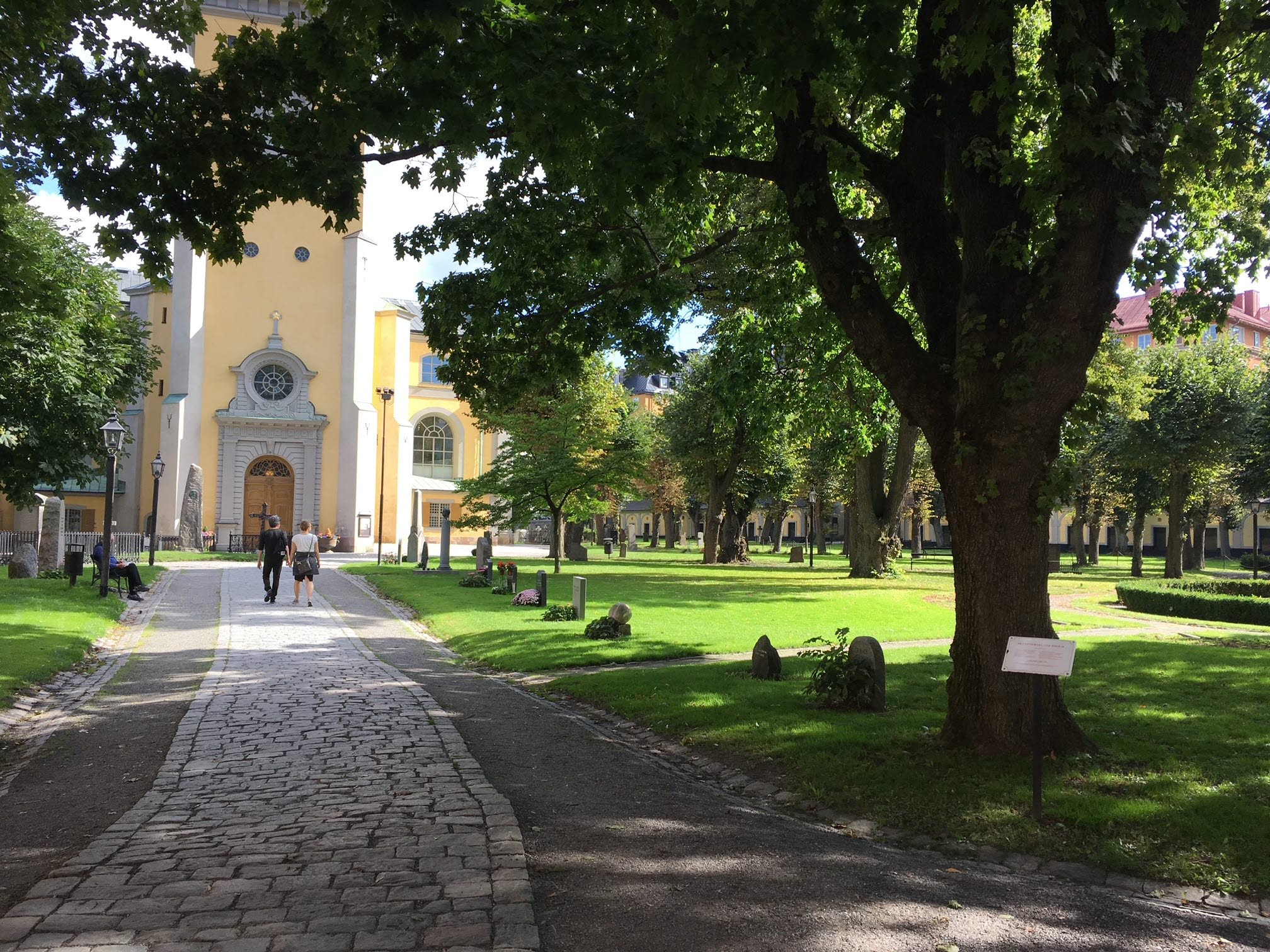 Människor som promenerar på en lummig kyrkogård i innerstan.