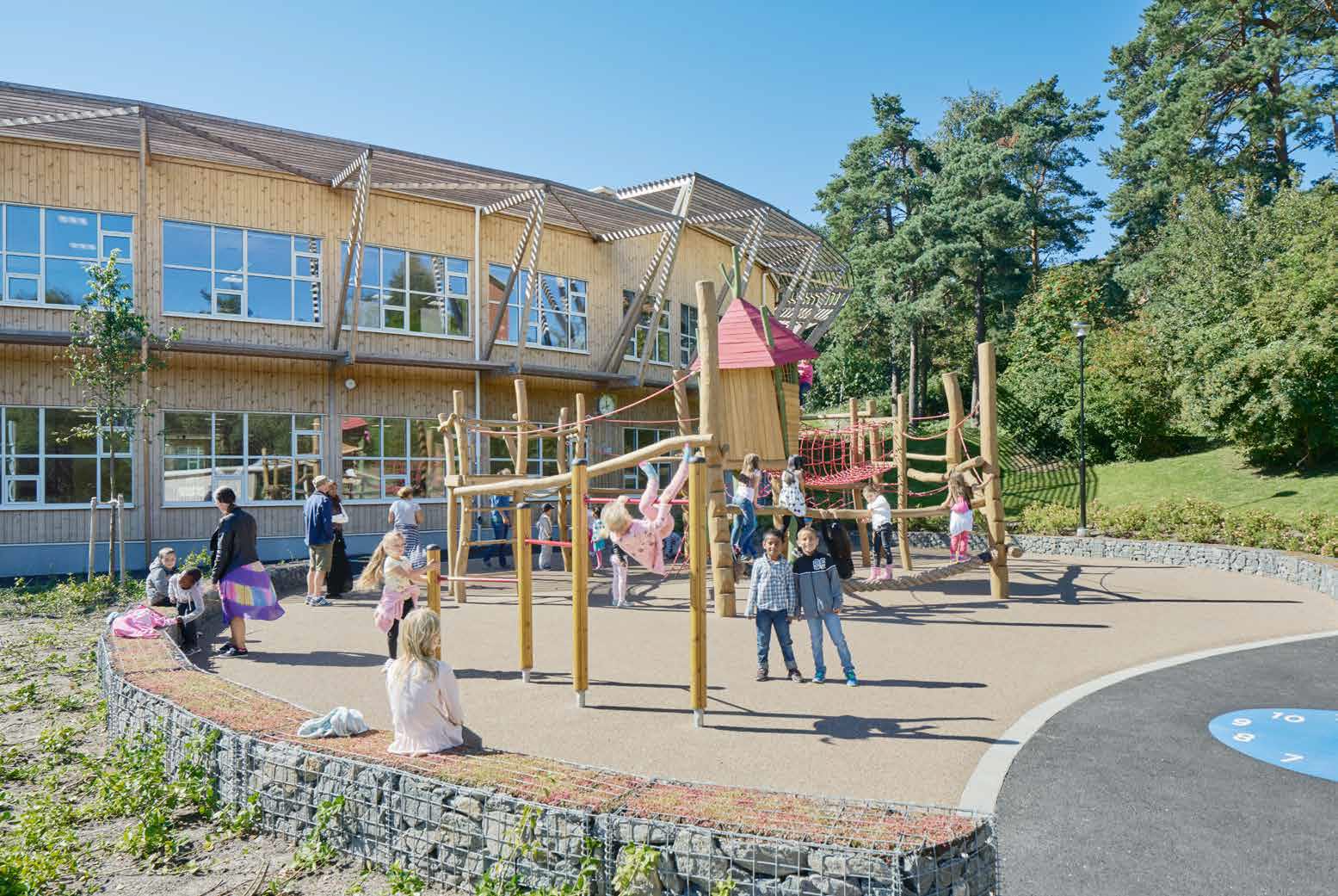 Lekplats utanför en skolbyggnad. Barn som leker och klättrar i klätterställningen.