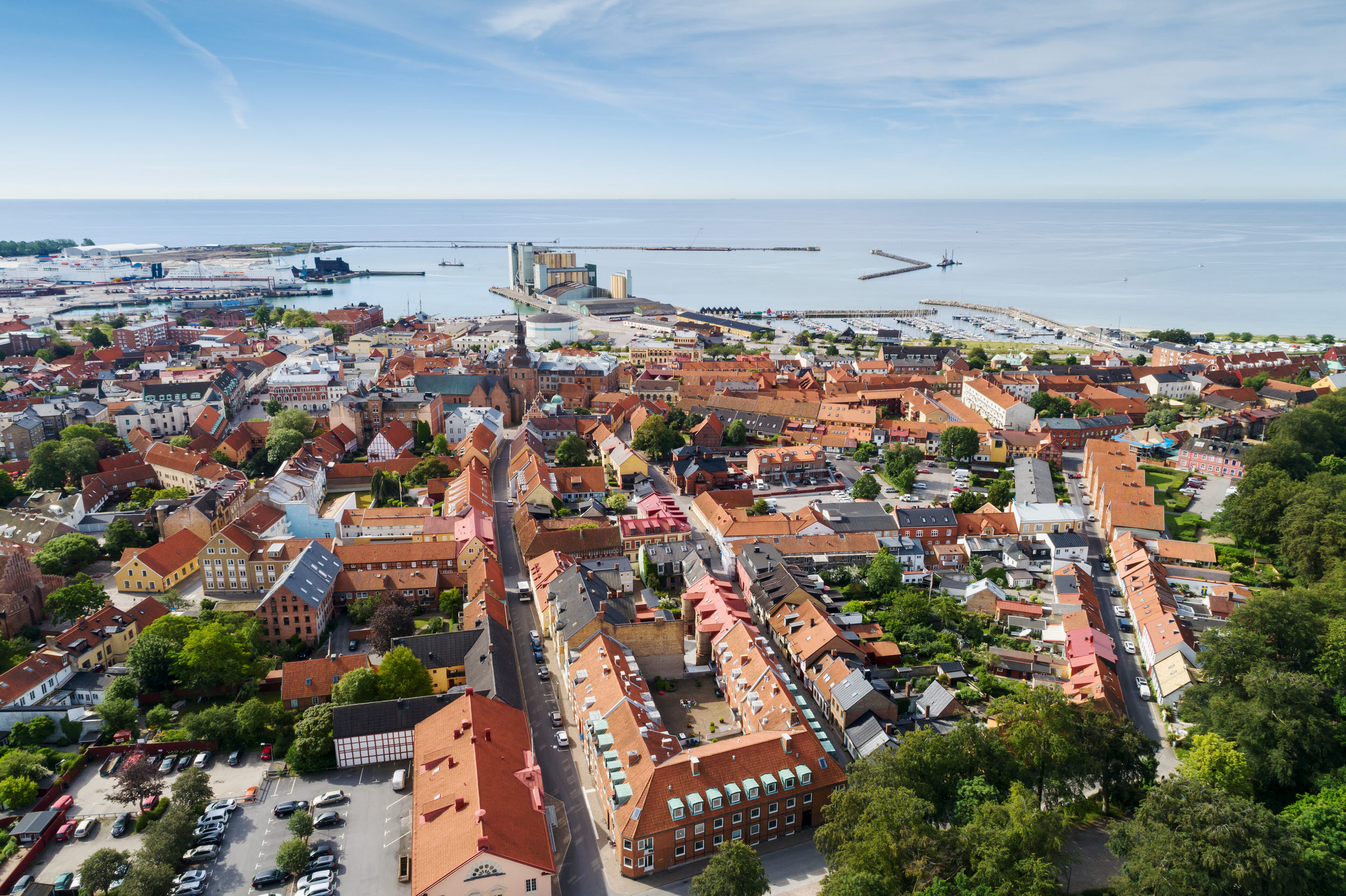 Flygfoto över stad med bostäder, lokaler industri och hamn med mera