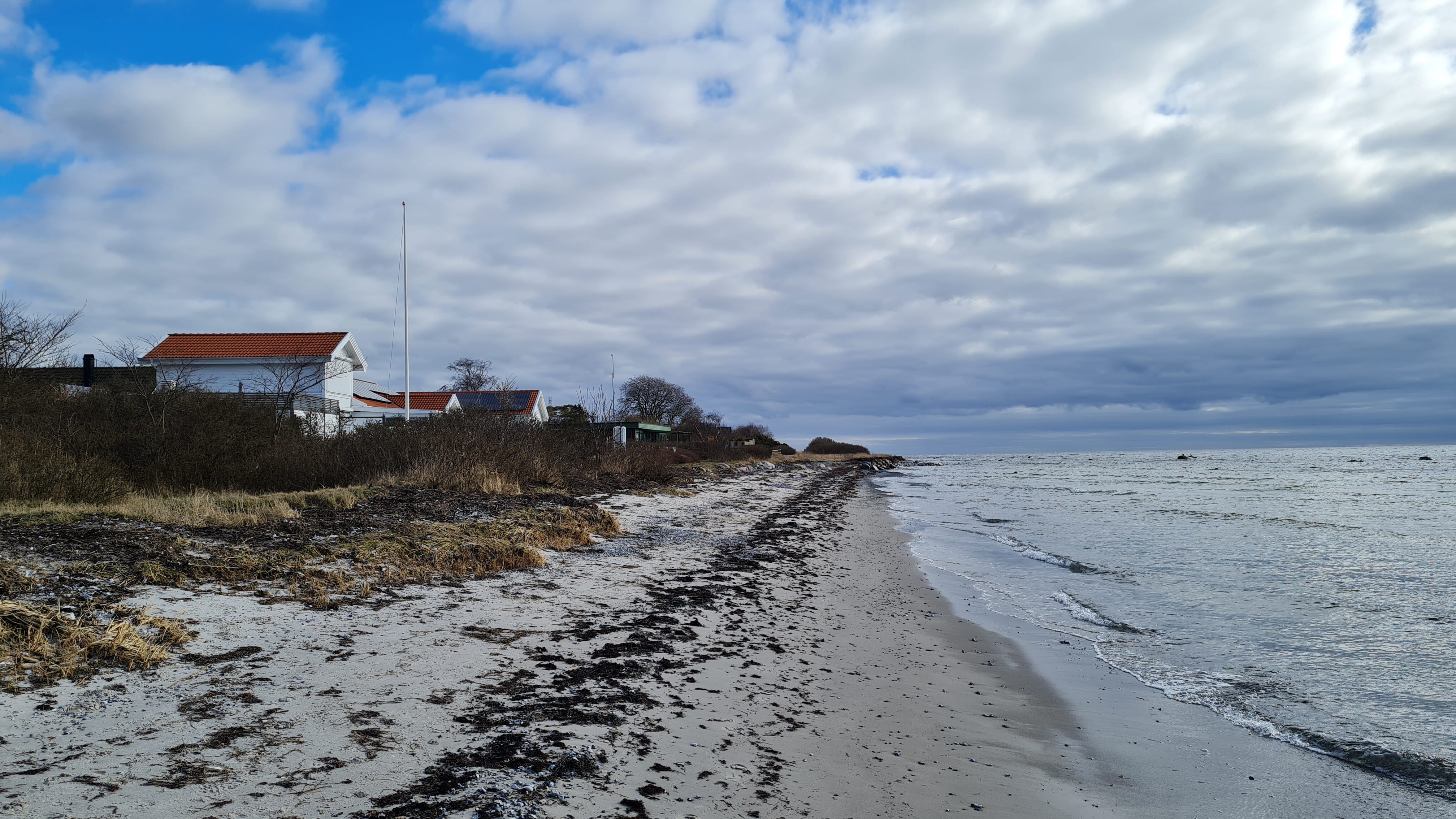 Ett hus på en stranremsa längsmed havet.