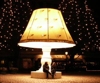 Två personer sitter på en bänk under en stor lampa. Foto: Mari Tastare