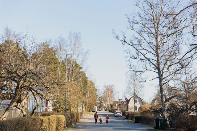 Familj på promenad på gata omgiven av villor.