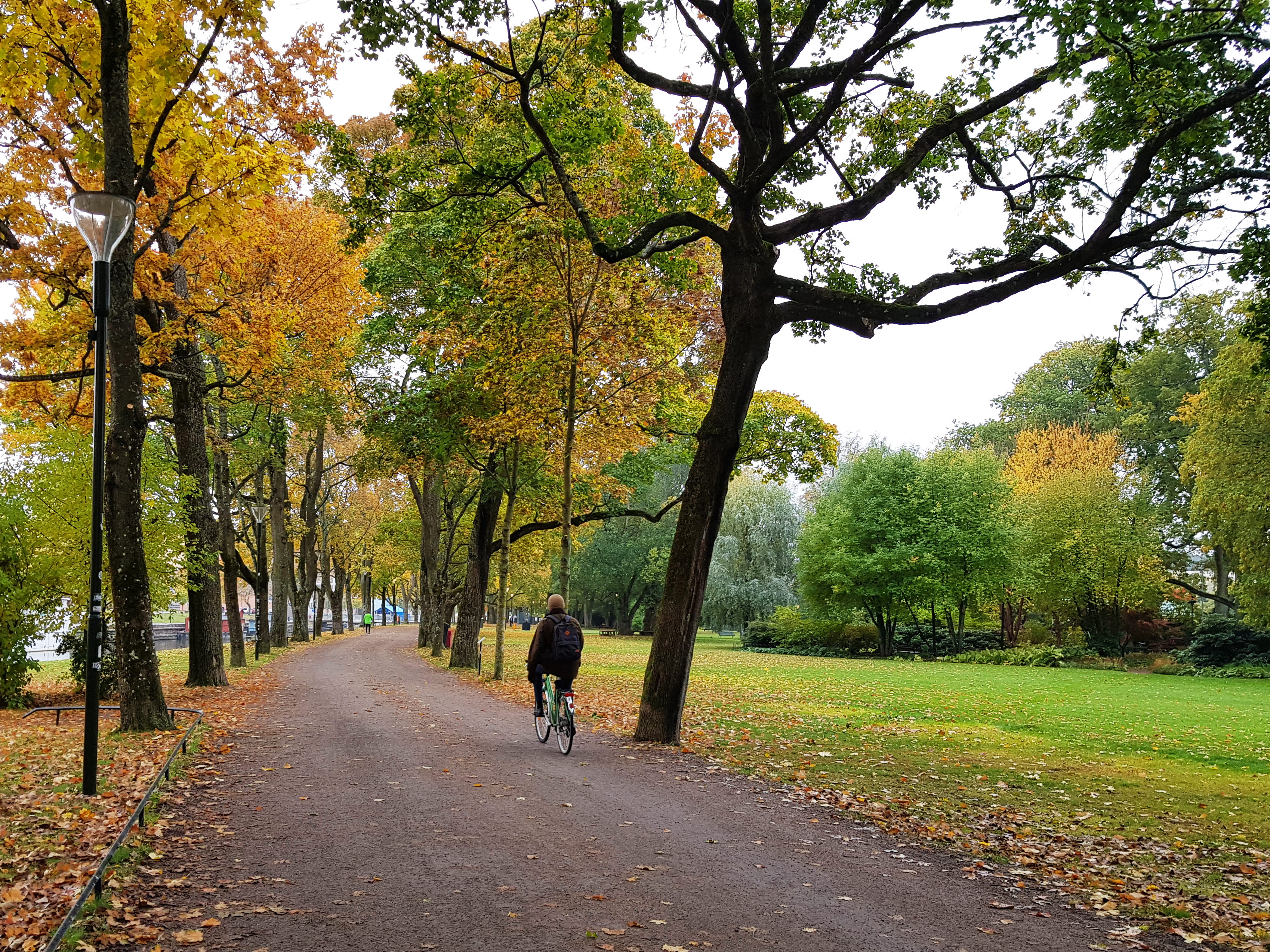 Bilden på man som cyklar och i bakgrunden längre bort en kvinna som promenerar på en gång- och cykelväg i Uppsala.