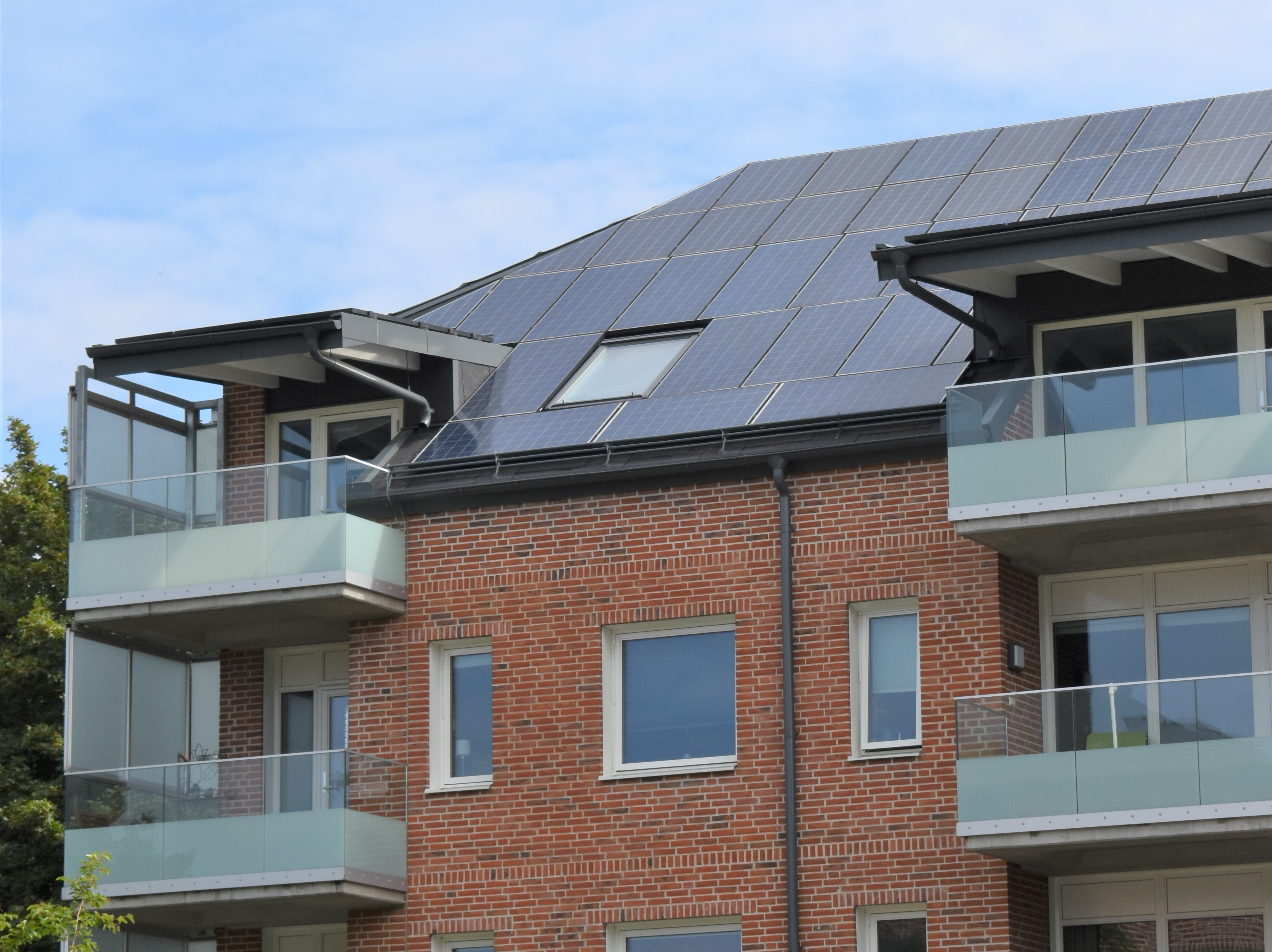 Flerfamiljshus i tegel med solceller på hela taket.