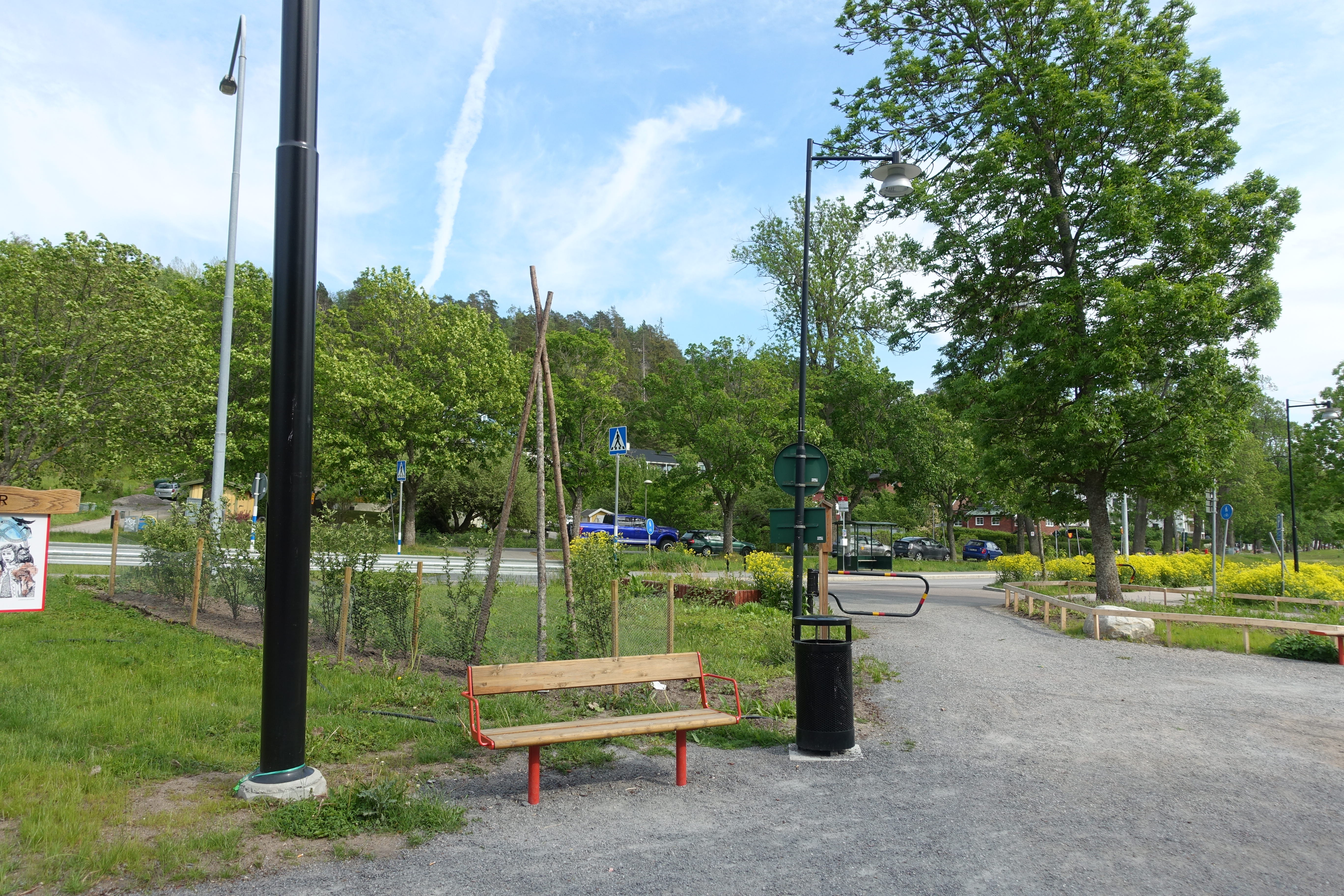 Grusgång med parkbänk, gräsytor och träd.