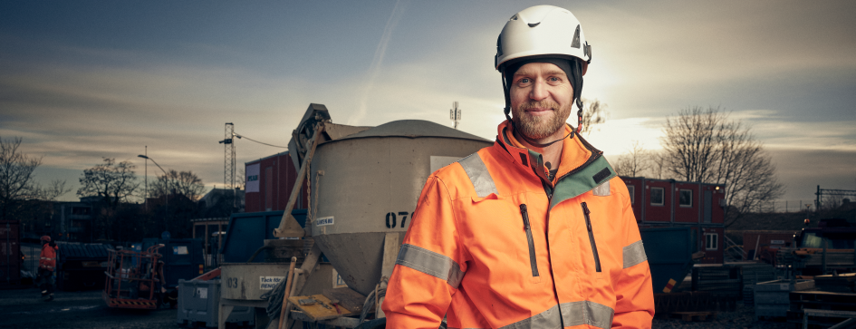 Gustav Holm i skyddskläder. I bakgrunden en cementblandare. 