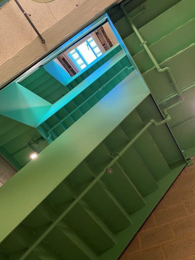 Foto underifrån på gröna metalltrappor i flera våningar.