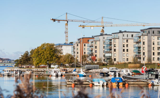 Småbåtshamn med byggkranar bakom flerfamiljshus. Foto: Scandinav/Marie Linnér