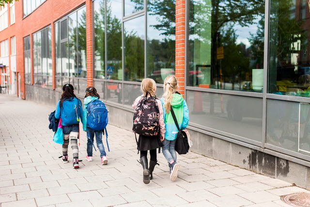 Fyra barn som går på en trottoar.