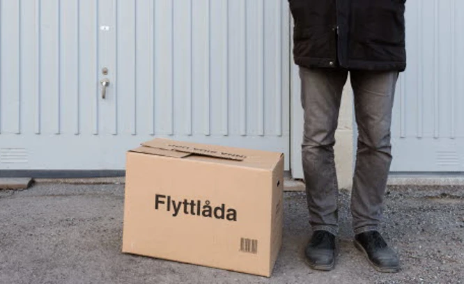 En person står vid ett garage med en flyttlåda. Foto: Jens Lindström/Scandinav