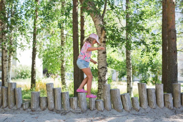 Flicka som balaserar på en gång av stående stockar.