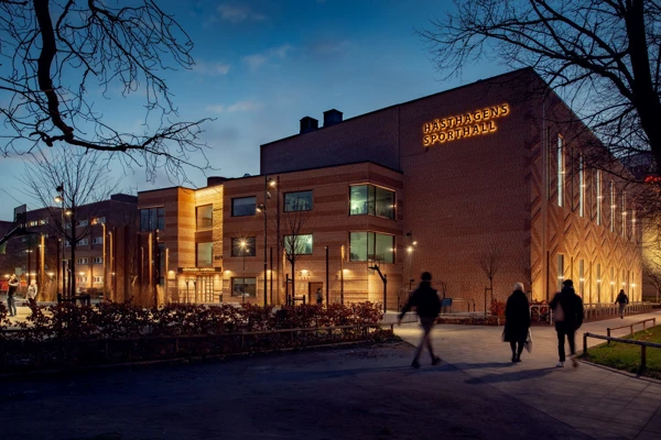 Tegelbyggnad med olika typer av belysning som lyfter fram olika delar av fasaden och arkitekturen.