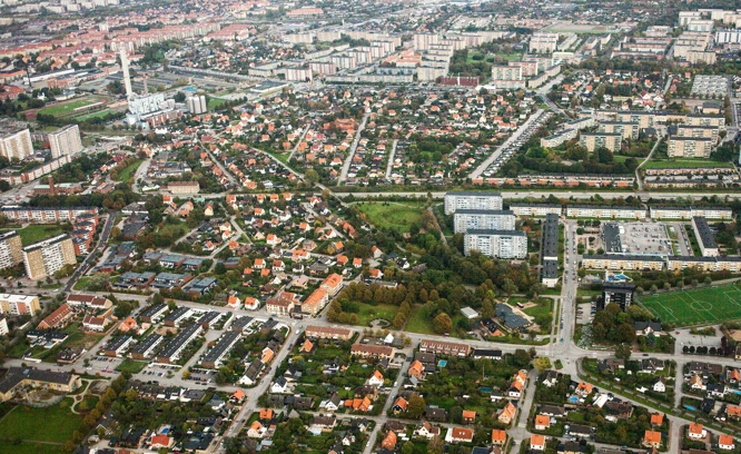 Flygfoto över en stad med tydliga stadsdelar, vägar och gröna områden.