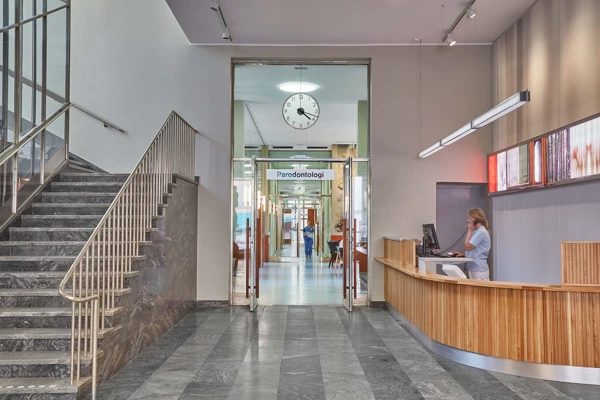 Trapphus med stengolv och en stor reception klädd i trä.