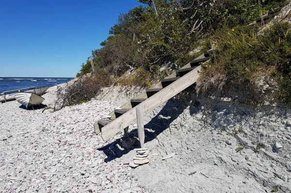 En trappa som leder ner till stranden saknar kontakt med marken till följd av erosion. Foto:n.