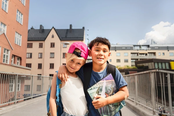 Bild på två barn som står framför några flerbostadshus.