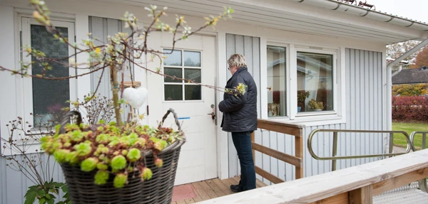 En kvinna sätter nyckeln i dörren på en enplansvilla.